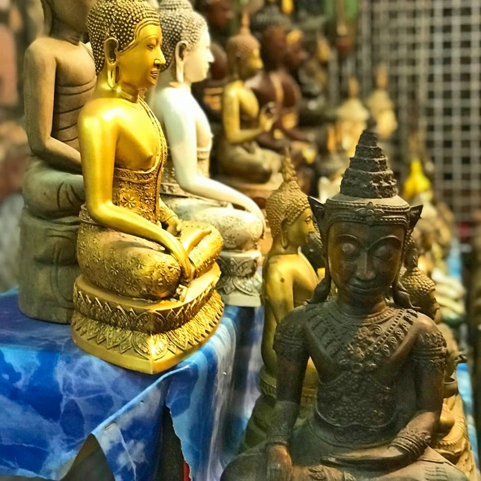 A collection of Buddha statues in various sizes and materials, including gold, white, and dark stone.